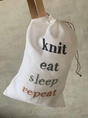 Project bag with embroidered text "knit, eat, sleep, repeat"